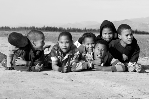 Seven kids lying on a dirt road on a farm in Africa.