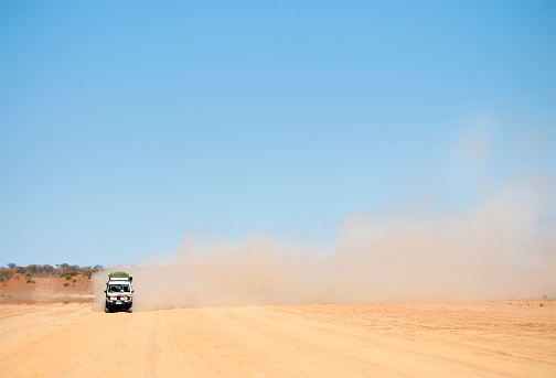 A 4x4 seen through heat haze travelling on an unsealed road in Australia's Northern Territory