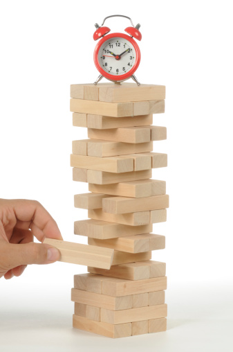 Wooden tower game and an alarm clock isolated on white background as a construction, architecture concept.