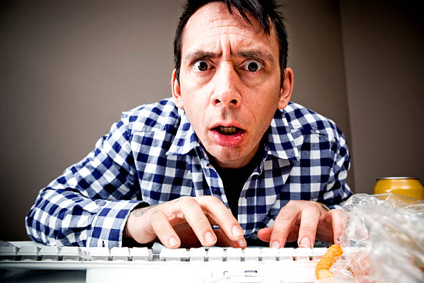 Man typing, looking into the camera as if it is the monitor, with a rushed/worried look on his face. This shot was taken at iStockalypse HQ 2009 in Calgary.