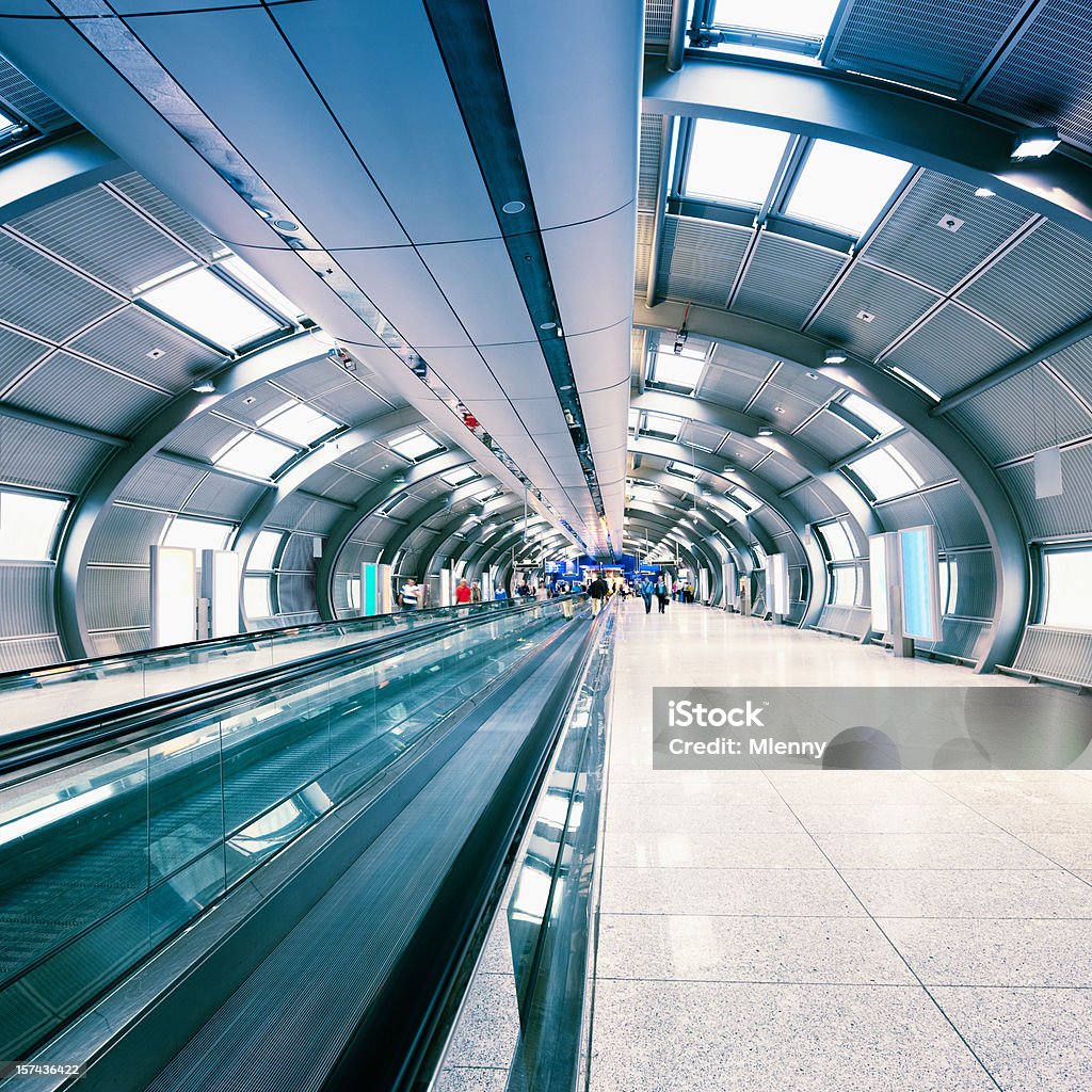 Futuristic Airport Walkway Tunnel Travellers walking through futuristic airport walkway connecting different terminals in modern airport. Long Time Exposure, Motion Blured. Unrecognizable People. Squared. People Stock Photo