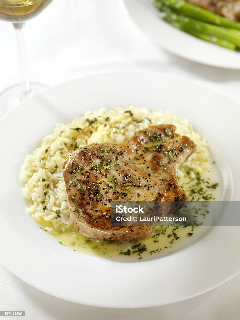 Chuleta de cerdo con una salsa de mantequilla de hierbas y arroz 2 - Foto de stock de Carne de cerdo libre de derechos