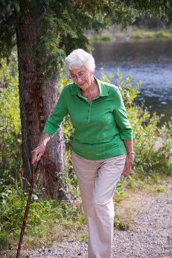 Healthy active elderly woman out jogging on a country road approaching the camera with a happy smile in a health and fitness concept