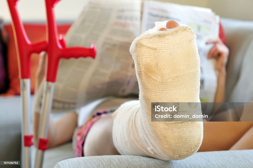 Frau mit gebrochenen Bein auf dem sofa liegende, bandage und Krücken - Lizenzfrei Frauen Stock-Foto