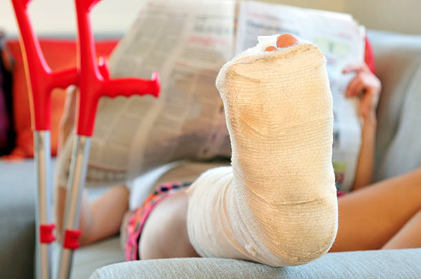 istock Woman with broken leg lying on sofa, bandage and crutches 157436752