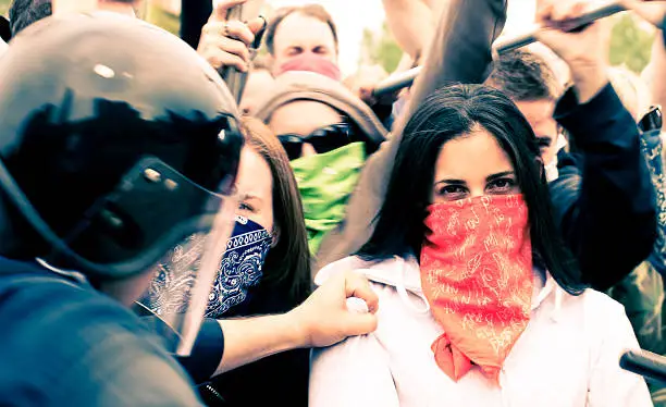 Female protester staring at camera while chaos surrounds her.