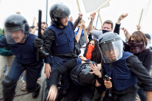 Riot Police Fight Angry Mob. This stock image has a horizontal composition.