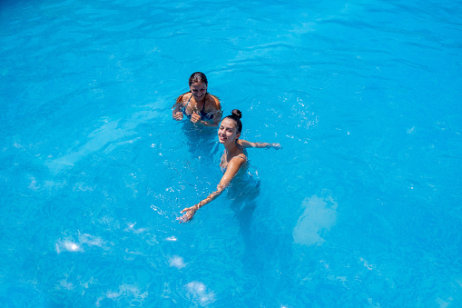 Two young girls in a pool of water.