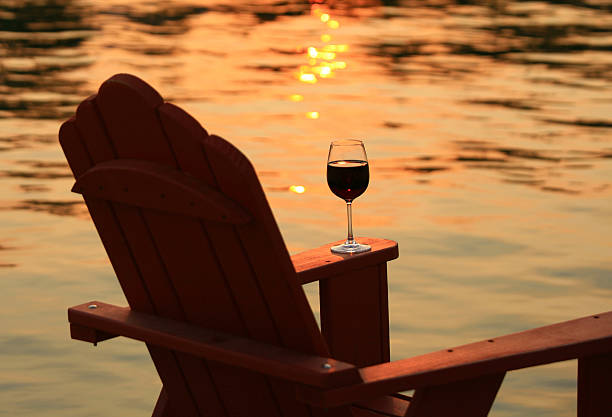 adirondack の椅子と夕暮れ時の湖グラスワイン - okanagan valley ストックフォトと画像