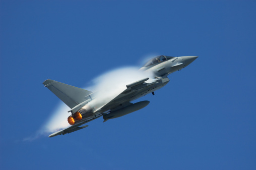 Military jet at high speed creating a pressure wave.