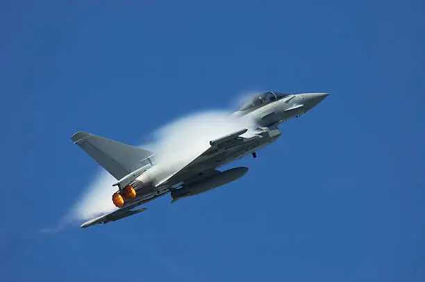 Military jet at high speed creating a pressure wave.