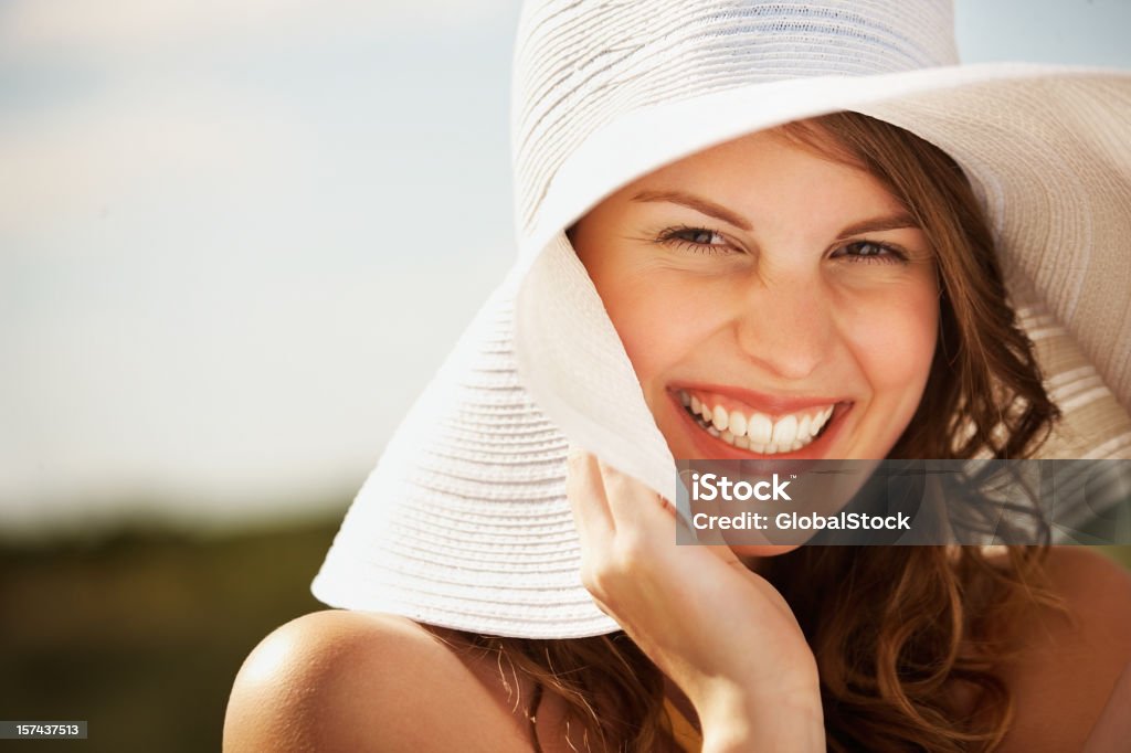 Close-up de uma linda jovem mulher vestindo um chapéu de palha - Foto de stock de Luz solar royalty-free