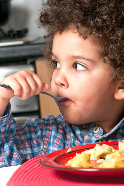 istock Kid eating pasta on her own 157437834