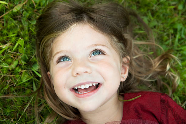 istock Little girl laughing and lying on grass. 157437964