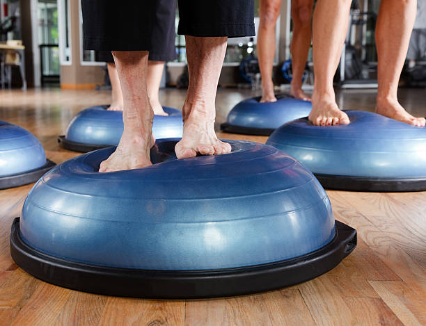 A close-up of the feet of class members using a balance training ball in a pilates class.