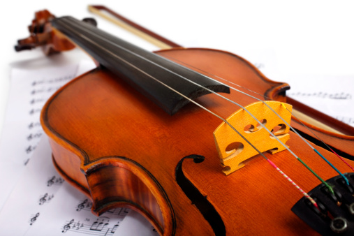 Cut image of a violin placed on musical notes over white background