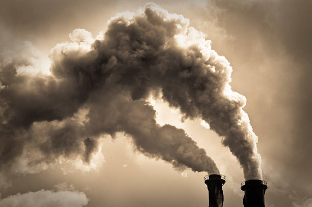 Industrial Air Pollution Toned monchrome image with billowing smoke coming from two chimneys.  Please note that limited film grain has been added during image processing. environmental damage photos stock pictures, royalty-free photos & images