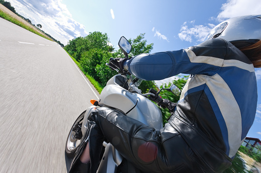 rear view of a woman riding her motorcycle, motion blur on ground, wheels and some of the background. 