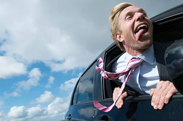 Excited businessman sticks his head out the car window and pants with joy like a dog