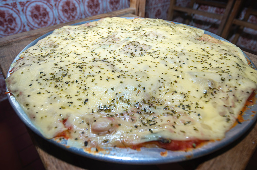 Pizza made with potato dough,mangerican cheese and oregano,natural light,homemade pizza,simple kitchen concept.