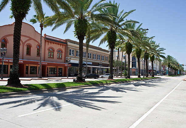 Daytona beach with road and trees A palm lined shot of downtown Daytona Beach Florida looking north on Beach Street. daytona beach stock pictures, royalty-free photos & images