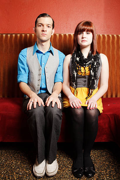 kitsch looking couple (or mother and son) having relationship problems posing on vintage couch