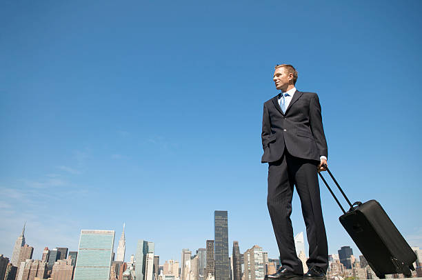 istock Young Businessman Standing with Suitcase above City Skyline 157439672