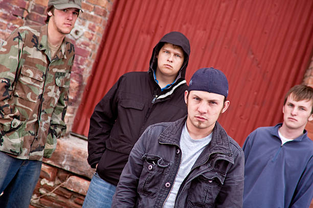 Four Urban Gang Members Four young gang members in an urban setting.  Camera angle is tilted slightly.  Selective focus on the face of the member in front gangster photos stock pictures, royalty-free photos & images