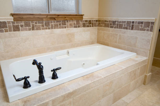 Tath tub with tan stone and cast iron faucet.