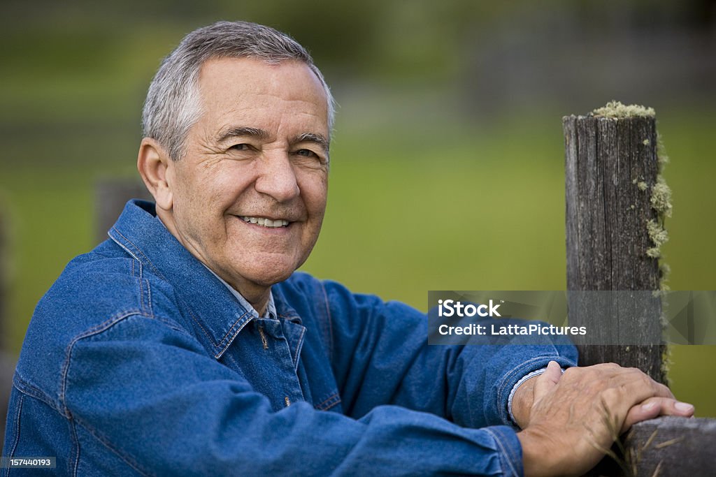 Sênior homem sorridente com os braços na cerca de madeira - Foto de stock de 60 Anos royalty-free