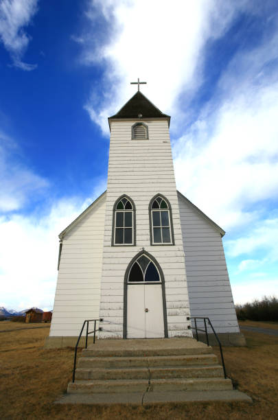 Old white church. Twin Butte, Alberta. This historic little United Church on the great plains is a beautiful and classic prairie structure. It is located on the scenic foothills of Alberta near Pincher Creek and Waterton National Park. Small churches were a significant part of prairie settlements and this little beauty is capture with nice detail and wonderful clouds behind the steeple. 