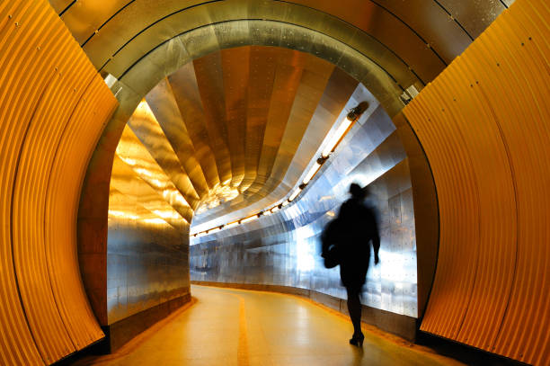 Industrial tunnel ventilation system with giant fan behind a grid and emergency exit sign