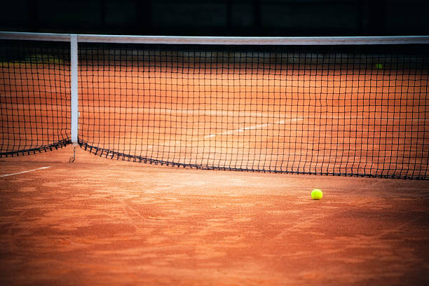 Tennis clay court Tennis ball in front of net on clay tennis court.    clay court stock pictures, royalty-free photos & images