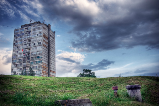 Run-down appartment building in southeast Europe set before a moody evening sky. High dynamic range photo. 