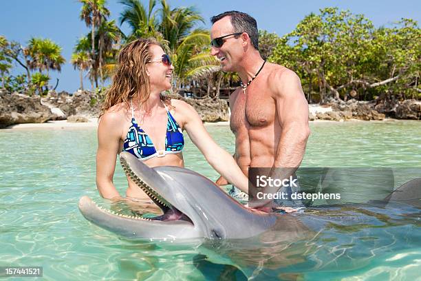 Adult Couple Enjoying Time In Water With A Dolphin Stock Photo - Download Image Now - Dolphin, Swimming, Caribbean Sea