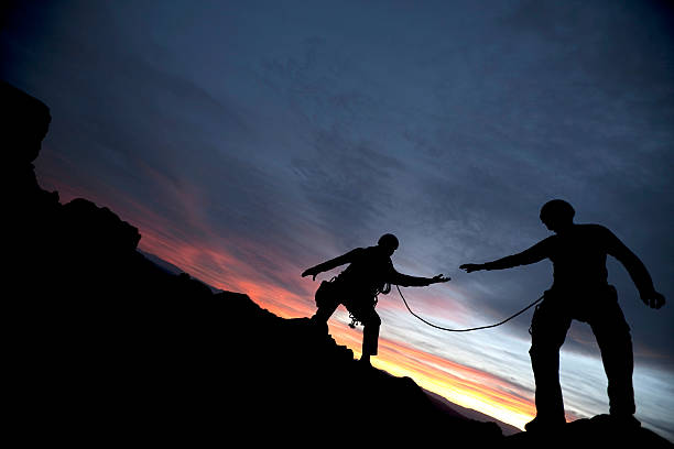 Climber reaching out to partner  extreme dedication stock pictures, royalty-free photos & images