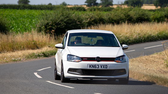 Turvey, Beds, UK - July 16th 2022. White 2013 Volkswagen Polo hatchback car driving on an English country road