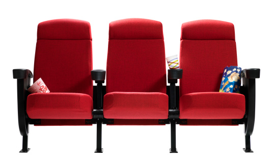 Three red movie theater seats with popcorn bags and barrel isolated on white background.
