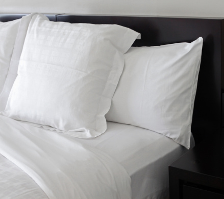 unmade bed with white linens close-up