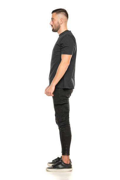 Side view of handsome confident cool young guy with t-shirt. Full body length portrait isolated over white background. Side view of handsome confident cool young guy with t-shirt. Full body length portrait isolated over white studio background. man standing profile stock pictures, royalty-free photos & images