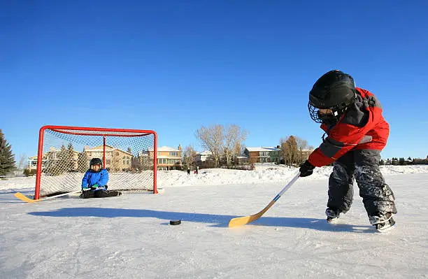 Photo of Young Caucasian Children Playing Ice Hockey on Outdoor Rink