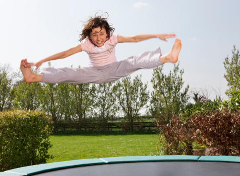 Girl playing on the trampoline doing splits,, acrobatic movements. Active children,, outdoors,, summer concept