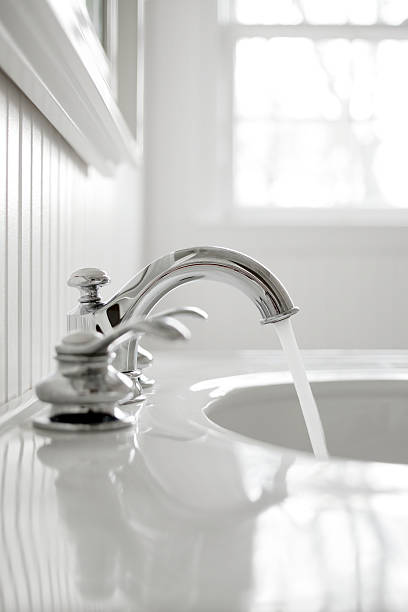 Faucet in a white bathroom Water running from a faucet in a day lighted white bathroom. bathroom sink stock pictures, royalty-free photos & images