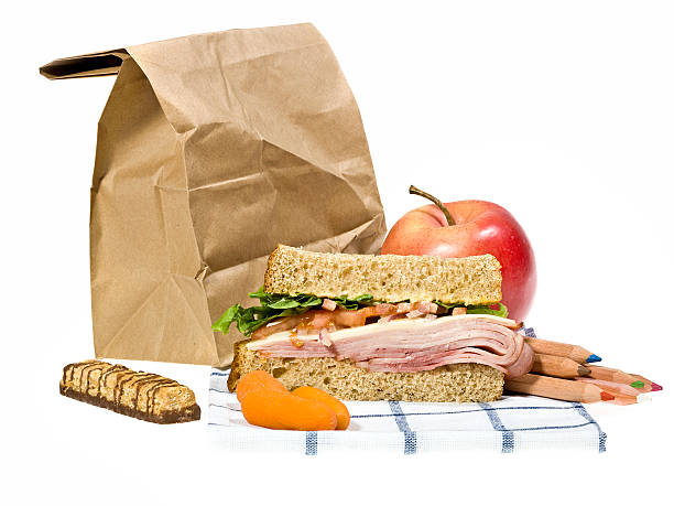 школьный обед р�ядом с коричневый бумажный пакет на белом фоне - завтрак в пакете стоковые фото и изображения
