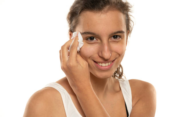 istock A smiling woman cleans makeup from her face with wet tissue on a white background 1574444005