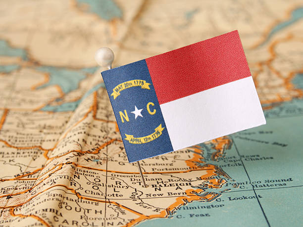 North Carolina North Carolina flag over more that sixty years old map pointing Raleigh city. Shallow depth of field state of north carolina map stock pictures, royalty-free photos & images