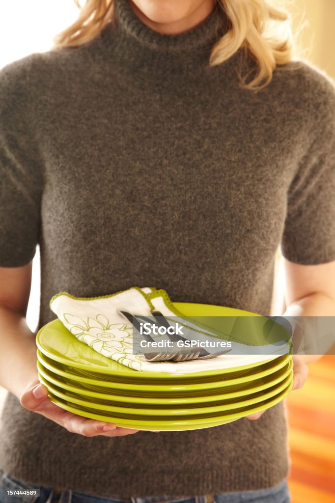 Attractive Woman With Pile of Green Plates Close-up of Woman carrying a pile of plates, napkins and forks in preparation for setting the table and dinner Carrying Stock Photo