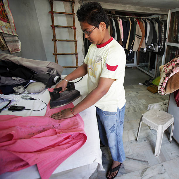 indischer mitarbeiter: kleidung und bügelbrett - arbeitsintensive produktion stock-fotos und bilder