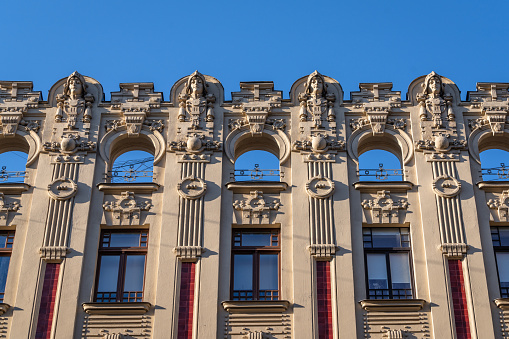 Elegant light grey facade with large windows and small white balconies with columns, in classical style .