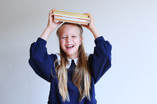 Photo of little school girl hold open book under head